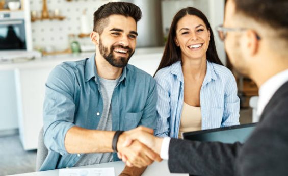 Real estate agent with couple shaking hands closing a deal and signing a contract